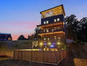 A multi-story building with a balcony, illuminated by string lights, and a sign that reads 'AFTER DARK'. - New Host Special • Indoor Pool • Glow Court • Golf Sim • Rooftop Hot Tub • Sauna (Pigeon Forge)