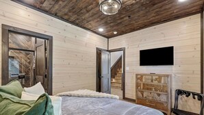 Ein Schlafzimmer mit einem Bett, einem Fernseher, einem Kleiderschrank und einer Treppe.