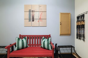 A red bench with striped cushions, a wooden door, and a wall-mounted ski rack. - Cozy Fall Foliage Retreat: Hot Tub, Firepit, Hikes, Lakes, and Indoor Waterparks (Blakeslee)