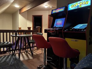 Ein Raum mit Spielautomaten, einem Tisch mit Stühlen und einer hölzernen Bank.