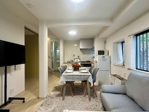 Een knus woongedeelte met een eethoek, kitchenette en een bank.
