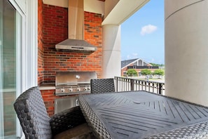 An outdoor patio with a brick grill, a table, and chairs.