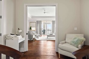 En gang der fører til en stue med sofa, stol og lampe.