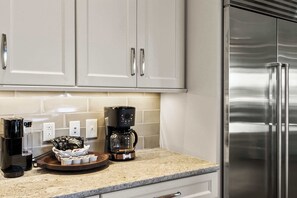 Et køkken med stålemmer, herunder et køleskab og en kaffemaskine.