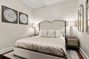 Une chambre à coucher avec un grand lit, deux tables de chevet avec des lampes et deux éléments décoratifs fixés au mur.