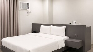 A modern hotel room with a large bed, bedside table, and a built-in wardrobe.