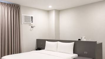 A modern hotel room with a large bed, bedside table, and a built-in wardrobe.