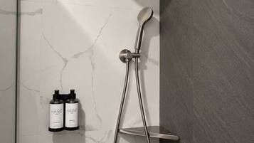 A modern shower with a handheld showerhead and a wall-mounted faucet.