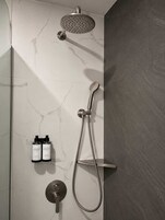 A modern shower with a handheld showerhead and a wall-mounted faucet.
