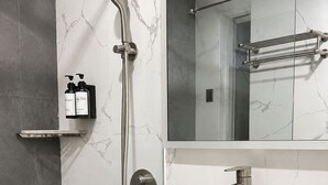 A modern bathroom with a white sink, a handheld showerhead, and a mirror above the sink.