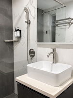 A modern bathroom with a white sink, a handheld showerhead, and a mirror above the sink.