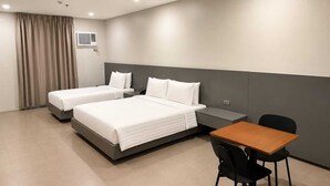 A hotel room with two beds, a desk, and a chair.