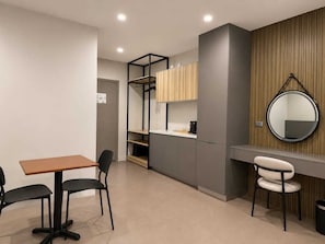 Una habitación moderna con escritorio, dos sillas, armario y espejo.