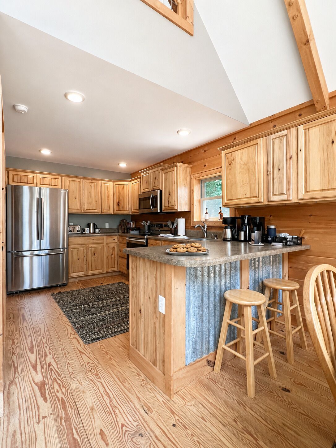 Una cocina moderna con armarios de madera, electrodomésticos de acero inoxidable y una isla central con taburetes.