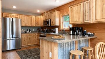 Una cocina moderna con armarios de madera, electrodomésticos de acero inoxidable y una isla central con taburetes.