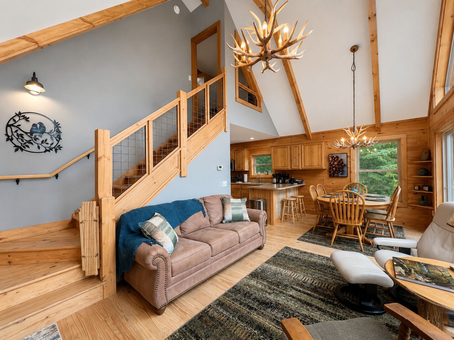 Ruime loft met een houten trap, een gezellig woongedeelte met een bank en stoelen, een eettafel en een keuken met houten kastjes.