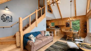 Ruime loft met een houten trap, een gezellig woongedeelte met een bank en stoelen, een eettafel en een keuken met houten kastjes.