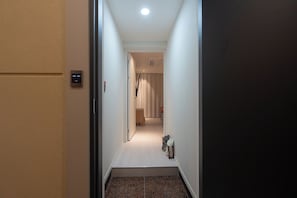 A hallway with a carpeted floor, a door on the left, and a light fixture on the ceiling. - Leclerc (Ulsan)