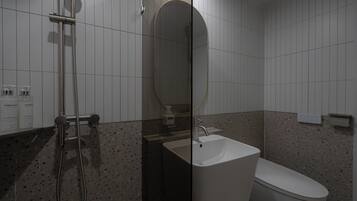 A modern bathroom with a shower, sink, and toilet.
