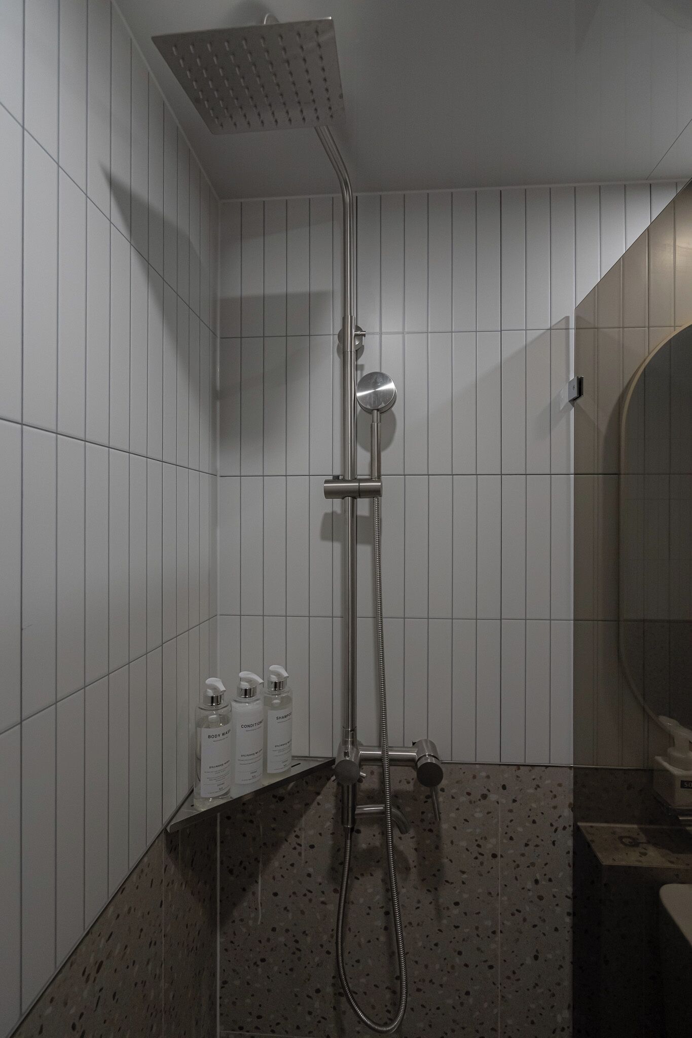 A shower area with a handheld showerhead, a wall-mounted showerhead, and a handheld shower hose.