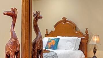 A bedroom with a wooden headboard, a bed with white linens, a colorful pillow, and a nightstand with a lamp.