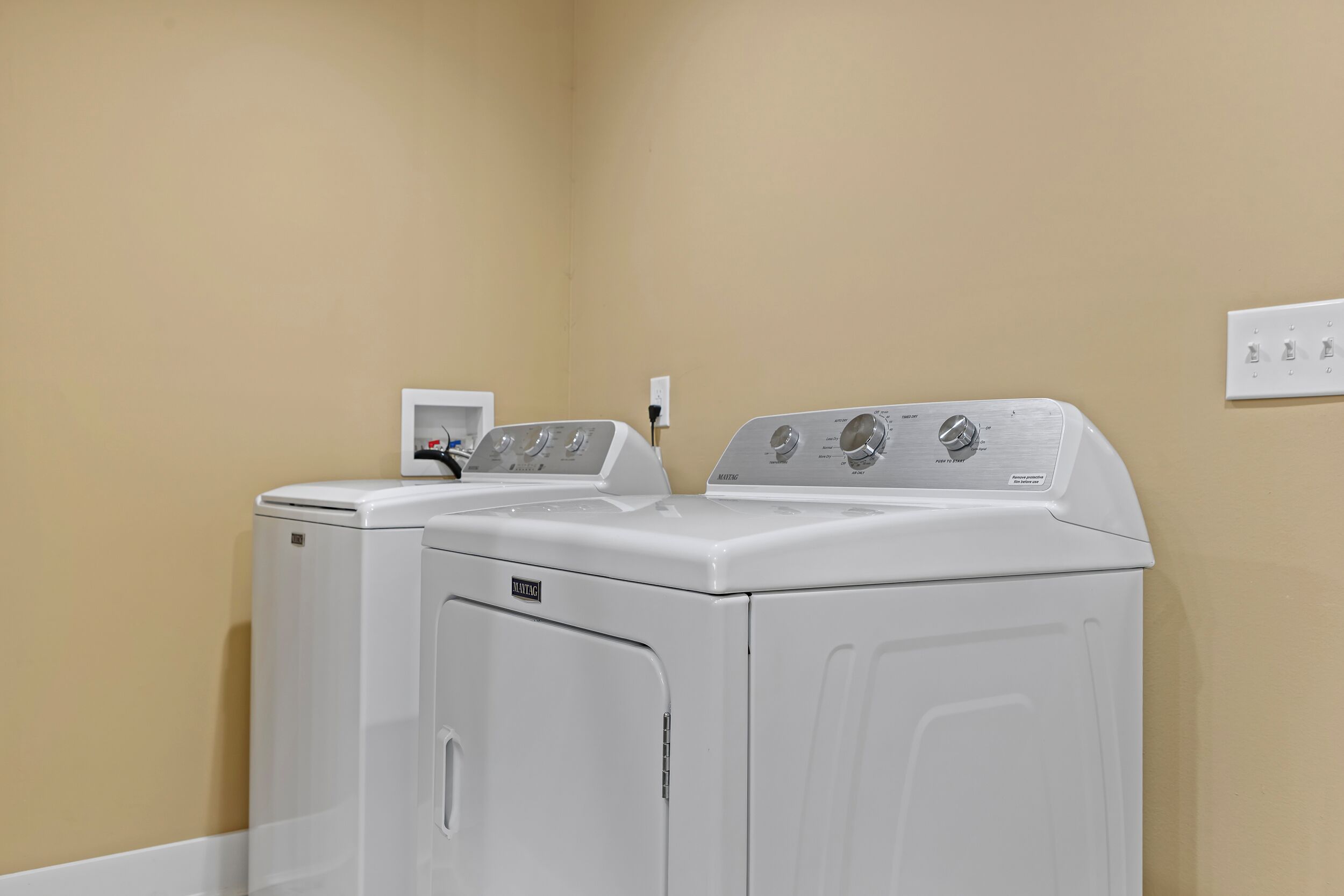 A laundry room with two white front-loading washing machines and a control panel.