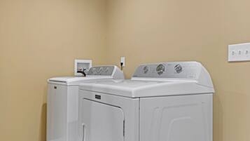 A laundry room with two white front-loading washing machines and a control panel.