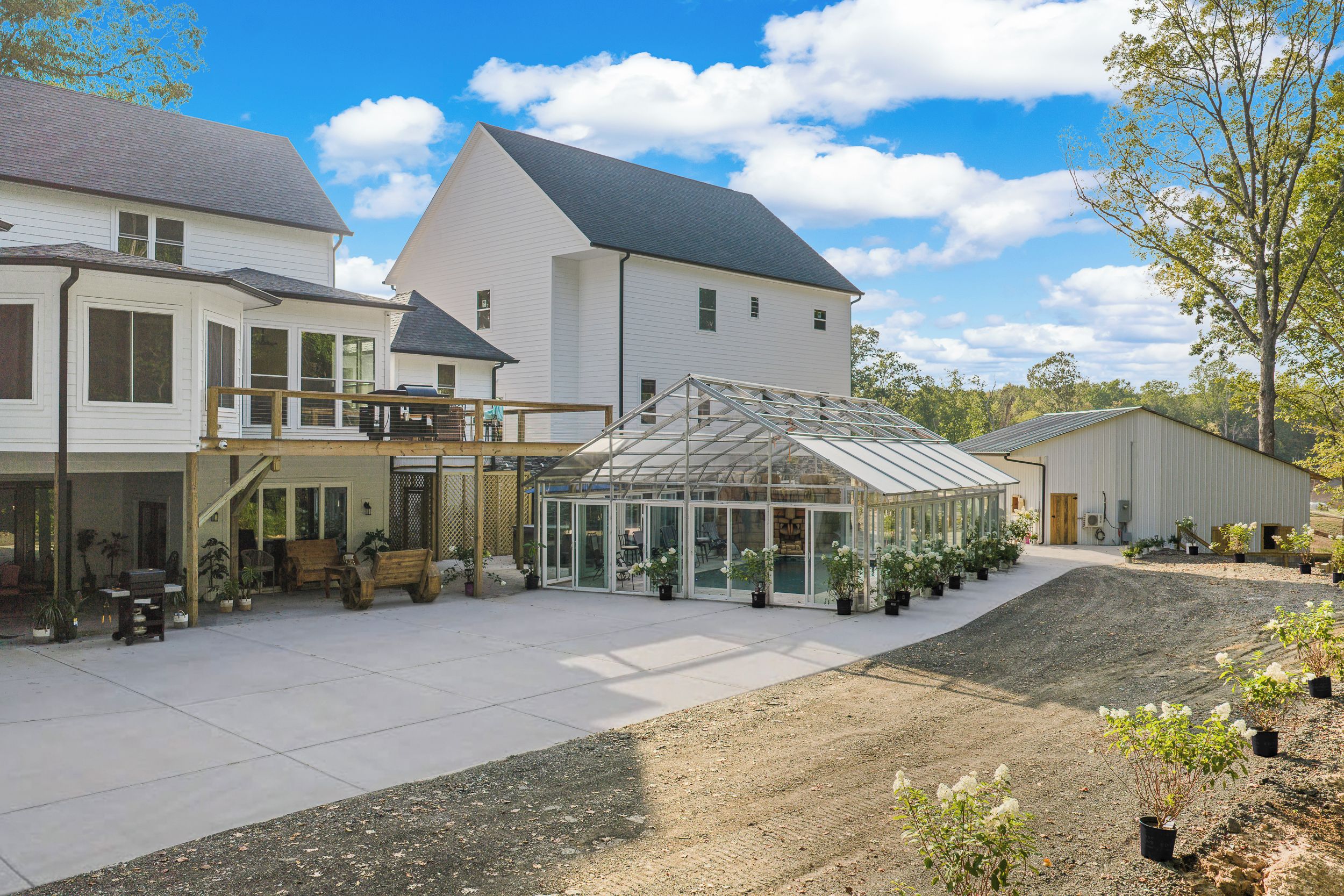 A residential property with a large house, a greenhouse, and a covered outdoor area with seating.