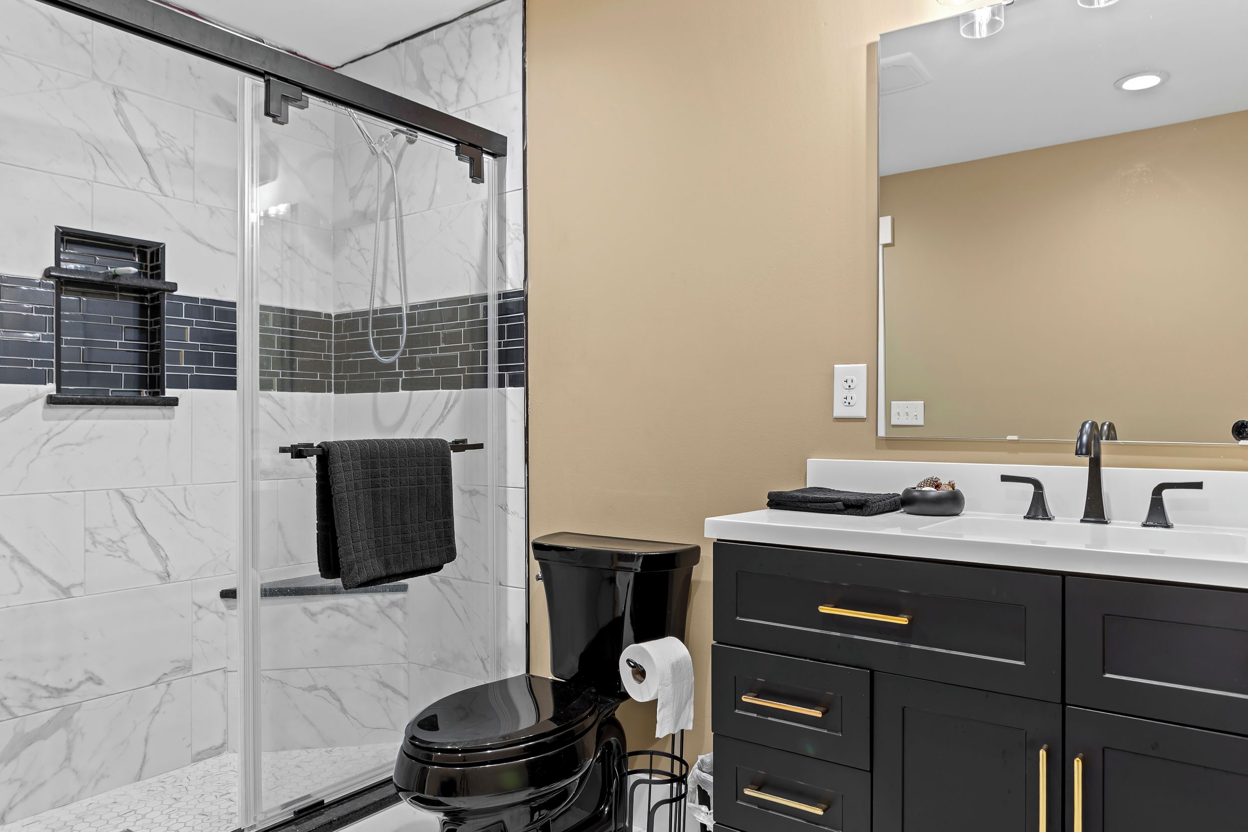 Une salle de bain moderne avec une douche à parois de verre, des toilettes et un meuble-lavabo avec un miroir.