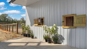 A white building with a corrugated metal exterior, a wooden fence, and potted plants.
