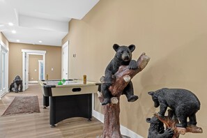 A room with a pool table, a bear statue, and a hallway.
