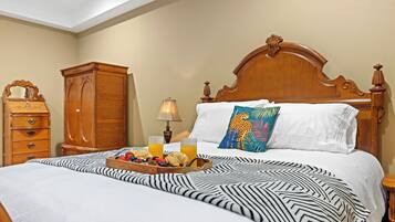 A hotel room with a large bed, a wooden nightstand, a dresser, and a lamp.