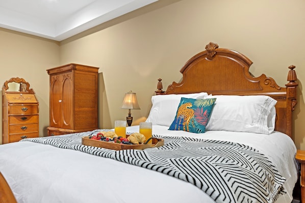 A hotel room with a large bed, a wooden nightstand, a dresser, and a lamp.