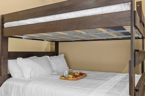 A bunk bed with white bedding and a tray of fruit.