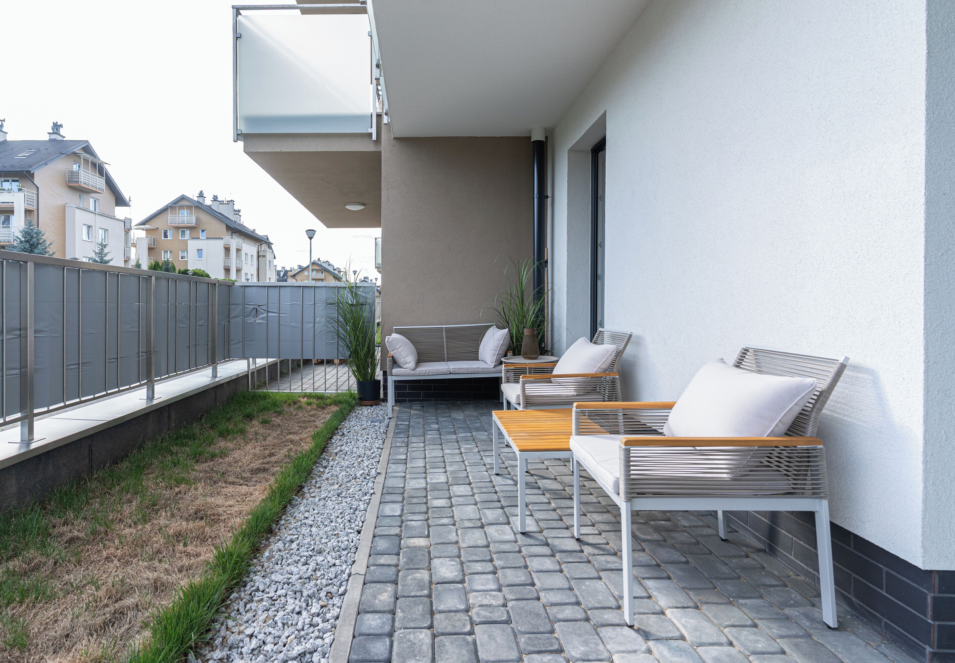 A balcony with outdoor furniture, a potted plant, and a view of neighboring buildings.