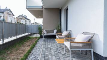A balcony with outdoor furniture, a potted plant, and a view of neighboring buildings.