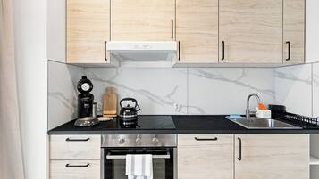 Een moderne keuken met houten kastjes, een zwart aanrecht, een roestvrijstalen oven en een koffiezetapparaat.