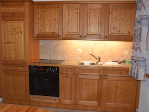 A kitchen with wooden cabinets, a stove, and a sink. - Favre OG Ost Appartement/Fewo, Dusche oder Bad, WC, 1 Schlafraum 2-Bett-Wohnung by Interhome (Matten  (St. Stephan))