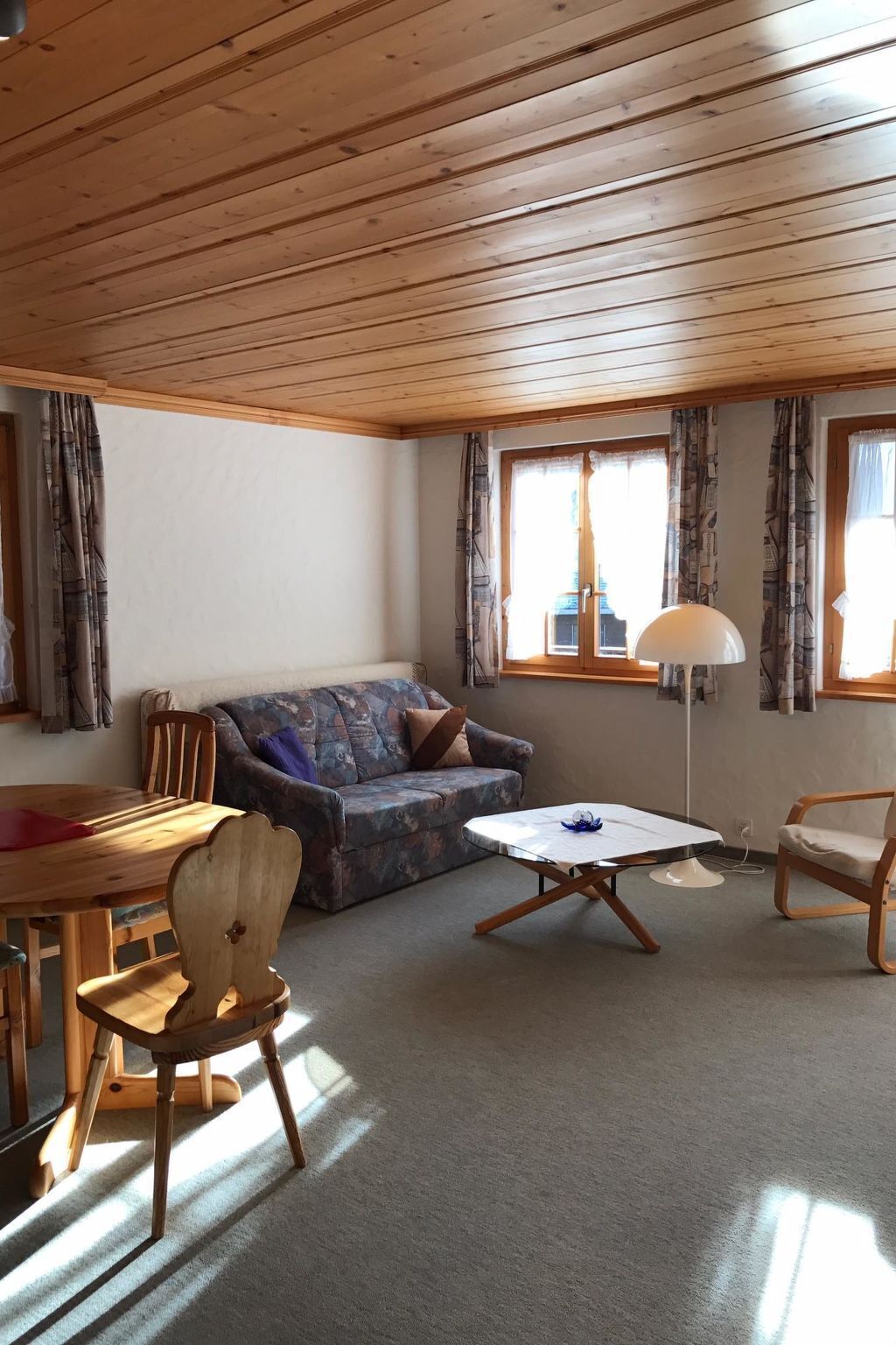 Un soggiorno accogliente con soffitto in legno, un divano, un tavolino da caffè e un tavolo da pranzo con sedie.