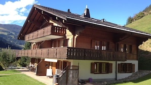 A two-story chalet with a balcony, a wooden staircase, and a view of the surrounding landscape. - Favre OG Ost Appartement/Fewo, Dusche oder Bad, WC, 1 Schlafraum 2-Bett-Wohnung by Interhome (Matten  (St. Stephan))