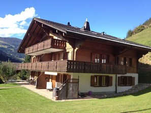 A two-story chalet with a balcony, a wooden staircase, and a view of the surrounding landscape. - Favre OG Ost Appartement/Fewo, Dusche oder Bad, WC, 1 Schlafraum 2-Bett-Wohnung by Interhome (Matten  (St. Stephan))