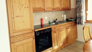 A kitchen with wooden cabinets, a black oven, and a tiled backsplash. - Favre OG Ost Appartement/Fewo, Dusche oder Bad, WC, 1 Schlafraum 2-Bett-Wohnung by Interhome (Matten  (St. Stephan))