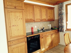 A kitchen with wooden cabinets, a black oven, and a tiled backsplash. - Favre OG Ost Appartement/Fewo, Dusche oder Bad, WC, 1 Schlafraum 2-Bett-Wohnung by Interhome (Matten  (St. Stephan))