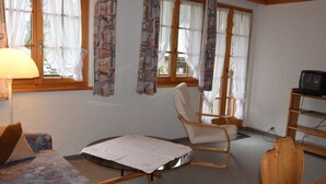 A cozy room with a sofa, a chair, a small table, and a television. - Favre OG Ost Appartement/Fewo, Dusche oder Bad, WC, 1 Schlafraum 2-Bett-Wohnung by Interhome (Matten  (St. Stephan))