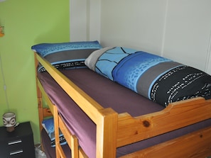 A bunk bed with a wooden frame, a purple mattress, and patterned pillows.
