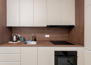 A modern kitchen with a built-in oven, a kettle, a sink, and a dishwasher. - Rondo Matecznego Signature Studio (Kraków)