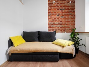 Un lit avec un cadre noir, deux oreillers noirs et un oreiller jaune.