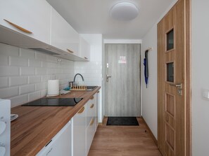 A modern kitchen with white cabinets, a wooden countertop, and a built-in stove. - Kamienica Rewolucji 23 Mezzanine Studio (Łódź)