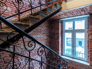 A brick interior with a metal staircase and a window overlooking a courtyard. - Kamienica Rewolucji 23 Mezzanine Studio (Łódź)