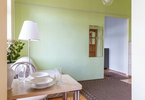 A dining area with a table set for two, a lamp, and a vase with flowers. - Szczecin Old Town Standard Apartment (Szczecin)